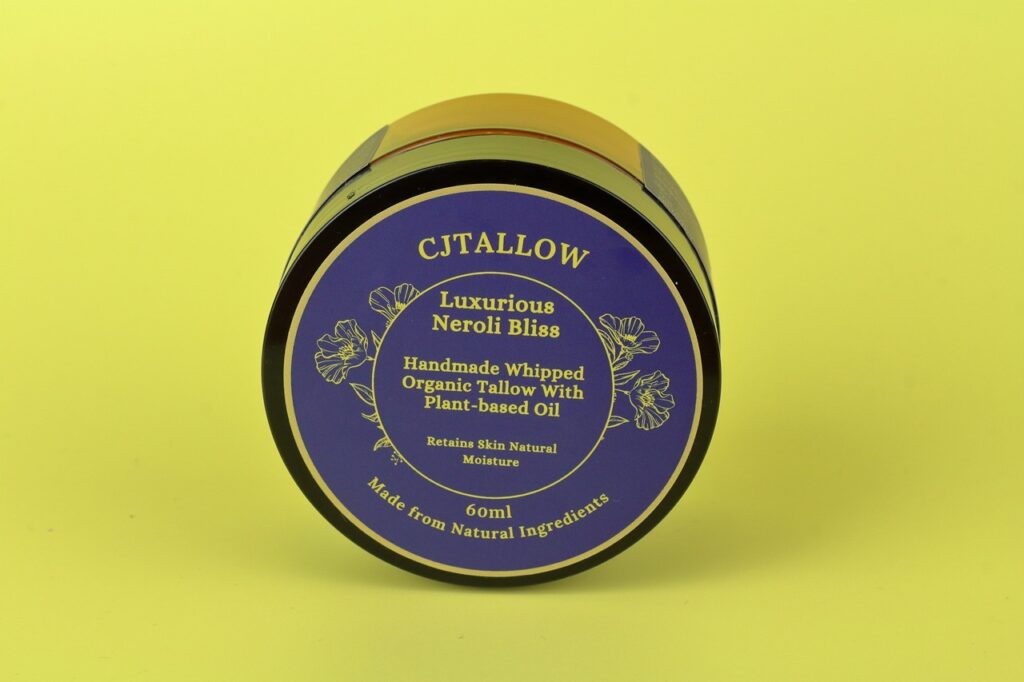 60ml jar of Neroli-scented whipped organic pasture-raised British tallow by CJTALLOW, blended with plant-based oils for natural skin hydration and nourishment. In Navy blue packaging. Made with natural ingredients to help retain skin's natural moisture.