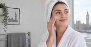 Woman enjoying a minimalist skincare routine in a bright UK-style bathroom, gently applying face moisturizer – CJTallow skincare